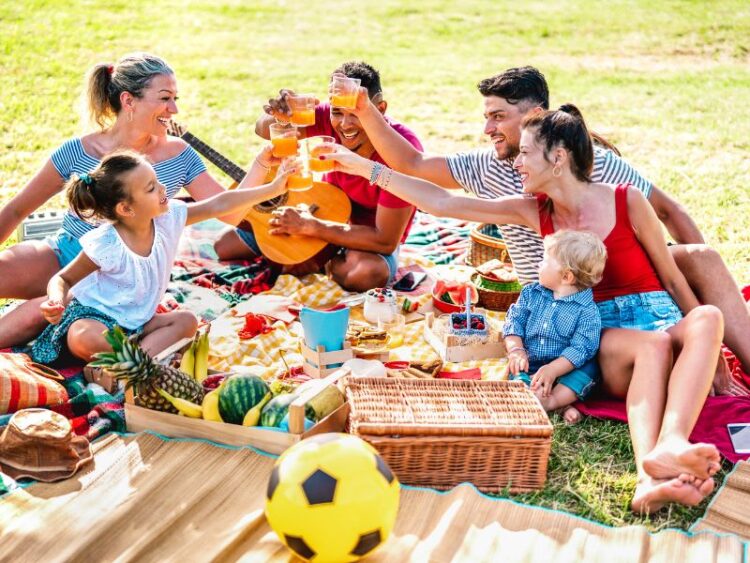 Families enjoying a picnic together outdoors, sharing food and laughter during a stress-free family vacation.