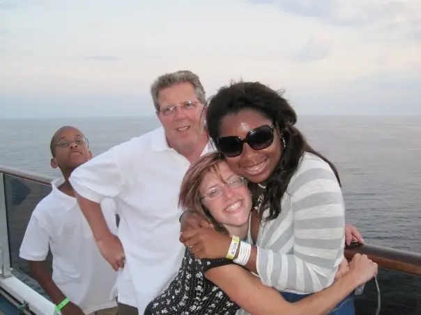 Family hugging and smiling on the deck of a cruise ship, enjoying quality time during a stress-free family vacation.