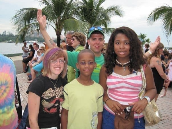 Family standing together at a cruise port with palm trees, beginning their stress-free family vacation.