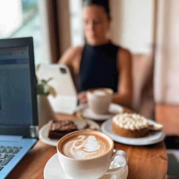 Writer reflecting in a cozy café with journal and coffee, preparing to share community gems