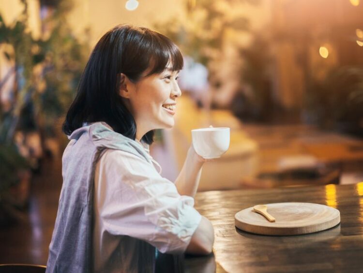 Person enjoying coffee slowly at a cozy café, practicing mindful travel and self-worth