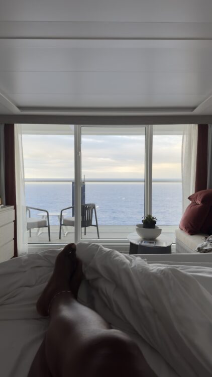 Peaceful morning view of the ocean from cruise cabin bed and balcony
