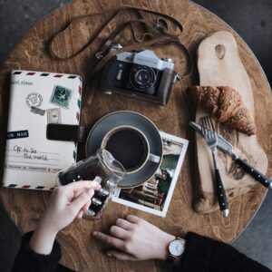 Travel journaling essentials with coffee, pastry, and camera
