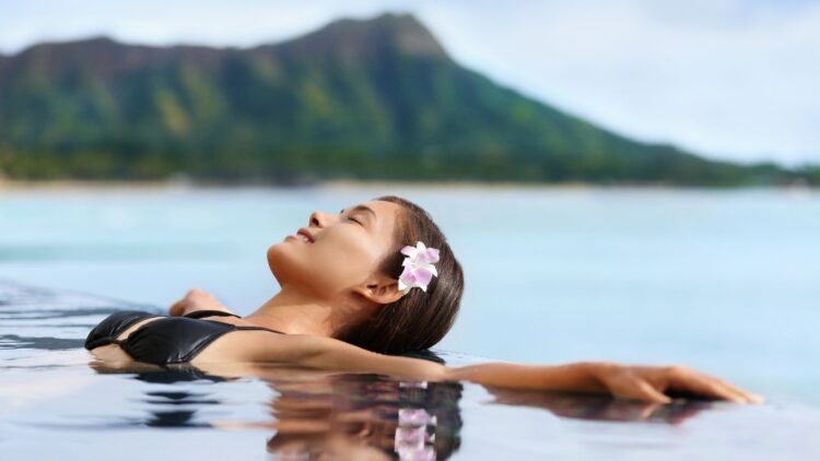 Wellness travel retreat, woman relaxing in pool with scenic view
