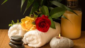 Spa setting with rolled towel, flowers, and candle symbolizing self-care rituals
