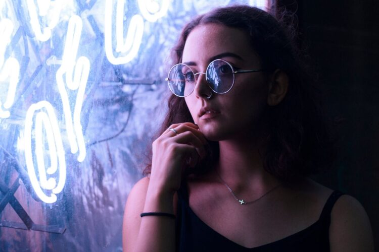 ntrospective moment as a woman gazes out thoughtfully near a neon sign, expressing emotional depth and internal processing