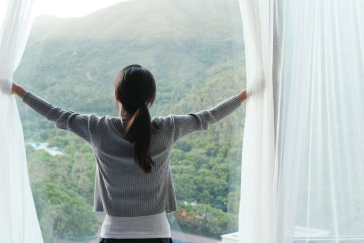 Mindful morning ritual of opening curtains to natural light and mountain views, symbolizing intention and emotional reset