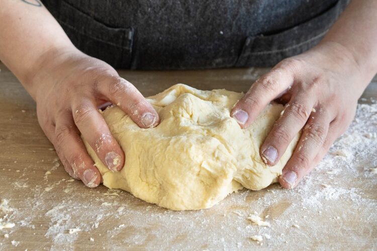 “Woman practicing mindful living by kneading sourdough dough, finding calm through hands-on sensory rituals in the kitchen.”