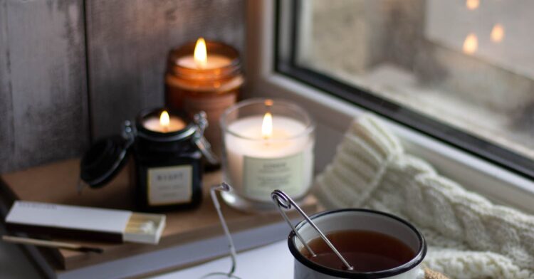 A warm autumn scene featuring tea, candles, and a cozy atmosphere by the window, ideal for a digital detox travel retreat.