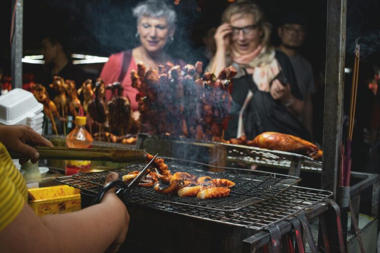 Traveler at eyeing a vibrant street food barbecue scene at Hội An night market, featuring grilled seafood and skewers.