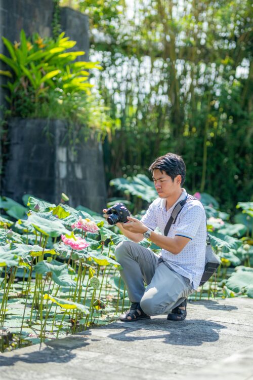 Traveler photographing the gardens of a free public botanical garden on a sunny day.
