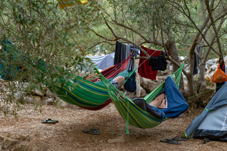 Two campers relaxing in hammocks amidst trees at Lastovo campsite, Croatia.