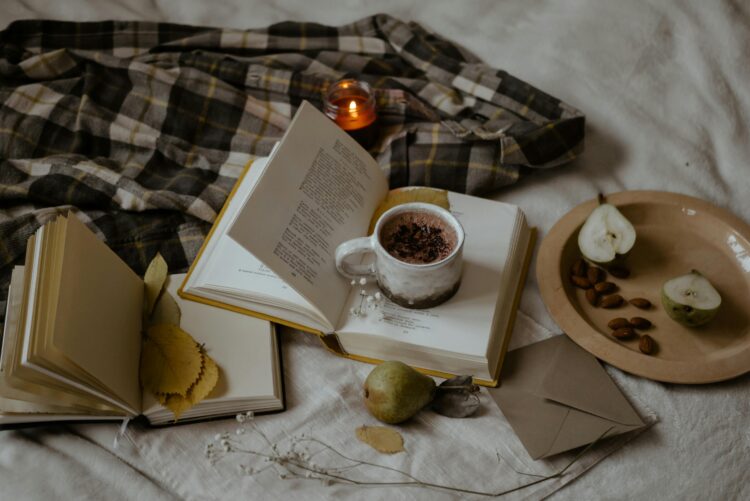 Warm and inviting setup with books, a hot drink, and autumn elements. 