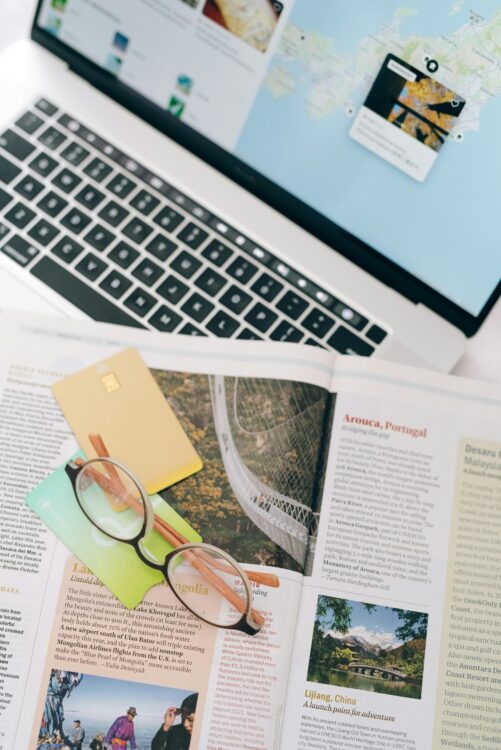 Traveler planning a trip with a travel book and laptop, budgeting for an affordable vacation