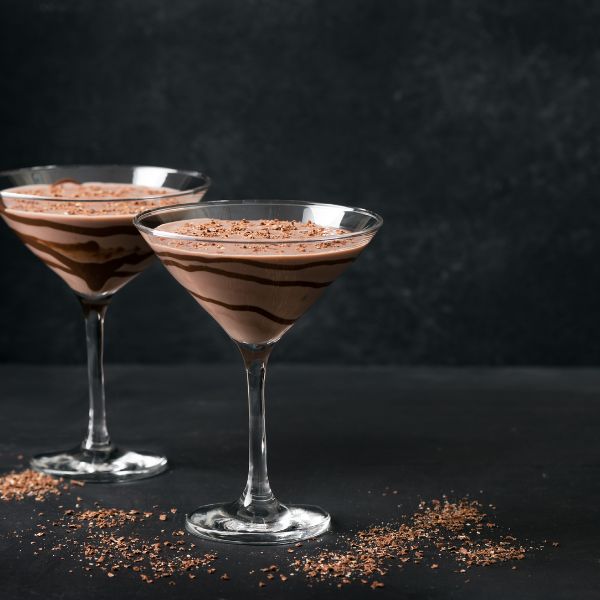 Two Chocolate Martinis with chocolate swirled in chilled glasses on a dark backdrop