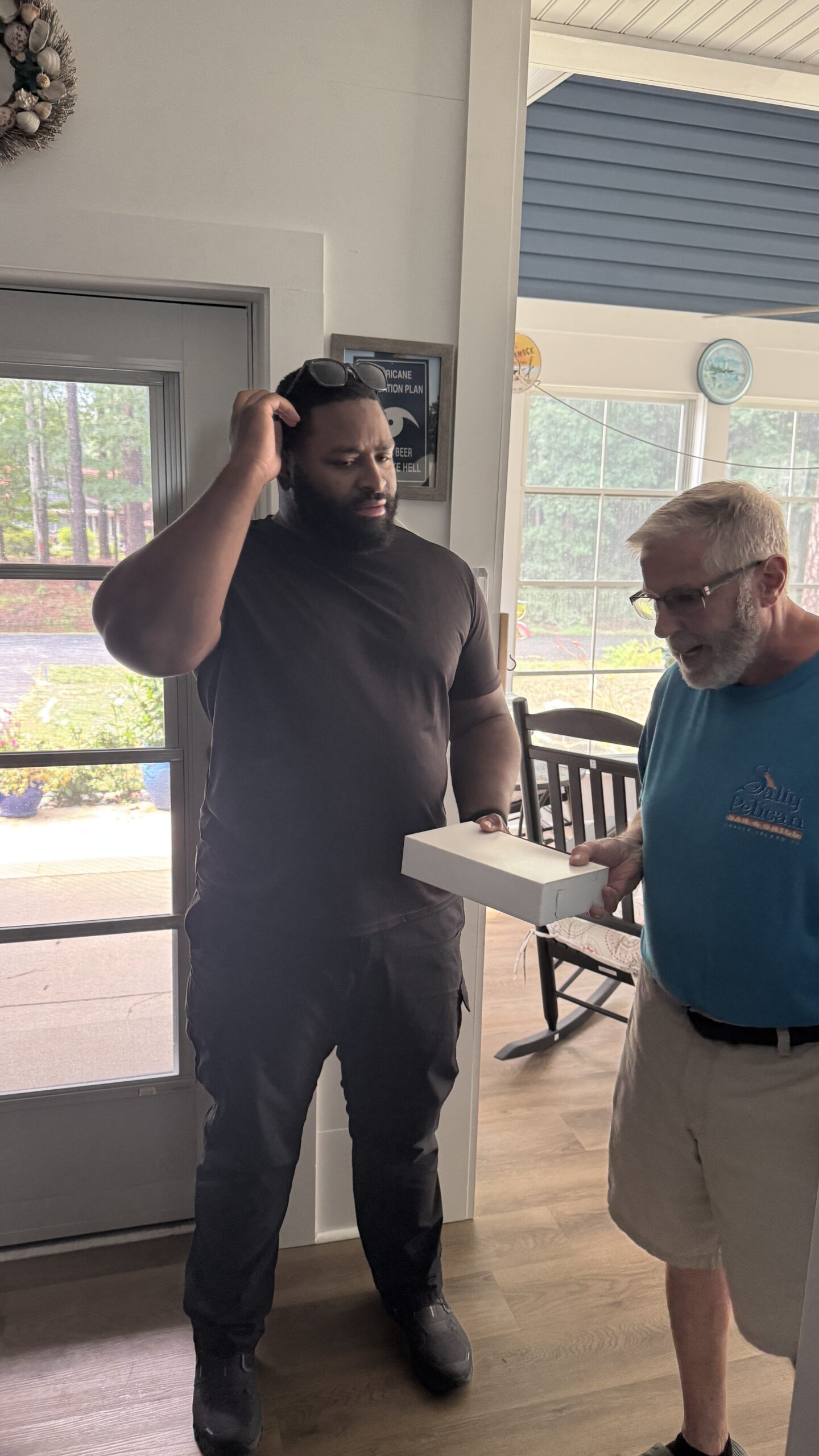 Son in-law and Father talking while holding a box of donuts, reflecting how casual conversations can still carry the weight of work stress into personal moments
