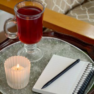 Evening gratitude ritual with journal, candlelight, and tea — creating a mindful wind-down atmosphere for rest and reflection.