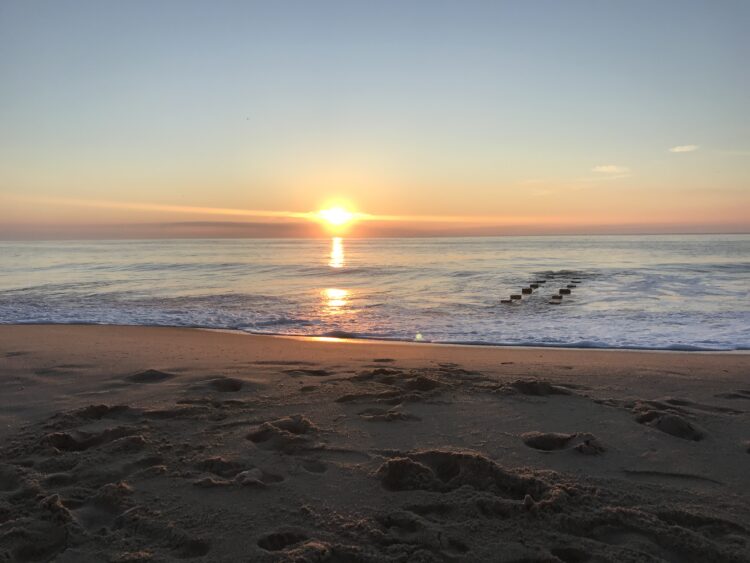 Peaceful sunrise over gentle ocean waves and sandy shore, symbolizing mindful travel, calm beginnings, and everyday restoration