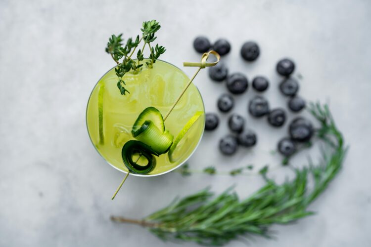 pexels-photo-24870610-24870610 Top view of a vibrant green mocktail garnished with rosemary, thyme, and blueberries, offering a refreshing taste.