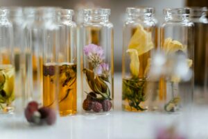 glass bottles filled with herbs, dried flowers, and fruit slices steeping in vodka and tequila for a mindful homemade infusion