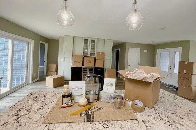 First Night Gift tea essentials arranged in a new kitchen with moving boxes still unpacked in the background.